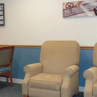 A waiting room with beige chairs and wall decorations.