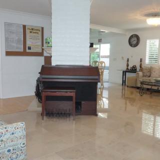 A spacious living room with a piano, tiled flooring, and modern furniture.