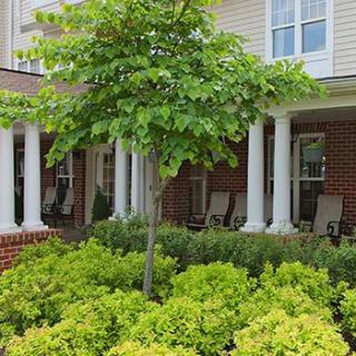 A charming house with a porch and lush greenery.