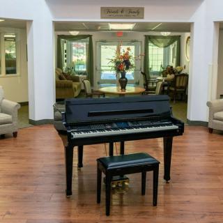 A piano and bench situated in a lobby with seating arrangements.