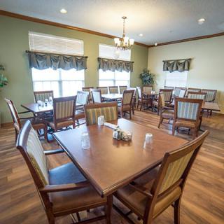 A well-lit dining room with neatly arranged tables and chairs.