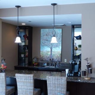 A modern kitchen space featuring a stylish counter with bar stools and pendant lighting.