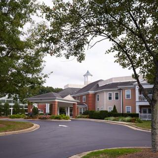 A view of a well-maintained building with a driveway and surrounding trees.