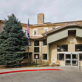 A building entrance with a flagpole and trees nearby.
