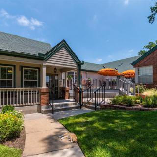 A charming house with a spacious porch and outdoor seating area, surrounded by a well-maintained lawn and garden.