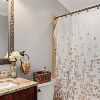A serene bathroom space featuring a shower curtain with floral patterns, a stylish mirror, and decorative elements.