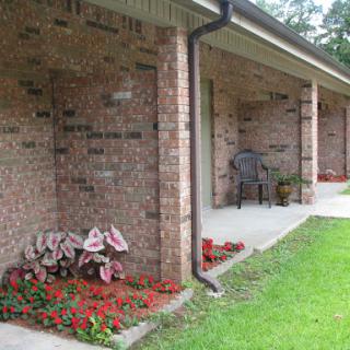 A cozy brick house with a well-maintained garden and porch.