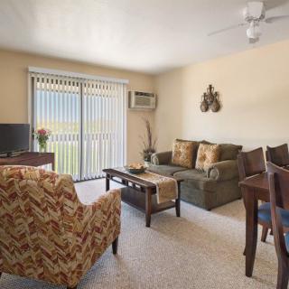 A cozy living room with comfortable furniture and natural light filtering through window blinds.