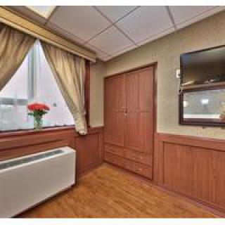 A cozy room featuring wooden paneling, a window with curtains, and a wall-mounted television.