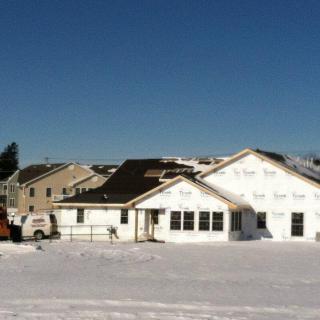A house under construction surrounded by snow in a winter setting.