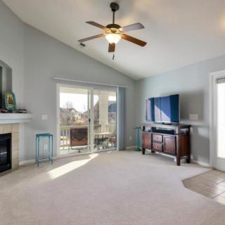 A bright living room featuring a ceiling fan, fireplace, and television.