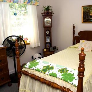 A cozy bedroom with vintage decor, featuring a grandfather clock and a twin bed.