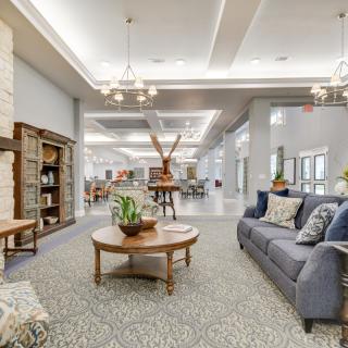 A modern and well-lit lobby area featuring comfortable furniture and elegant chandeliers.