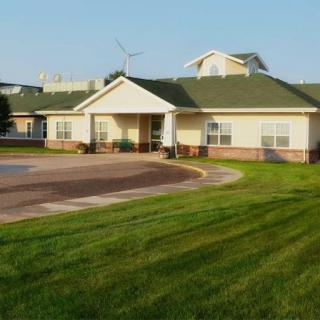 A well-kept residential house surrounded by lush green grass and a clear blue sky.