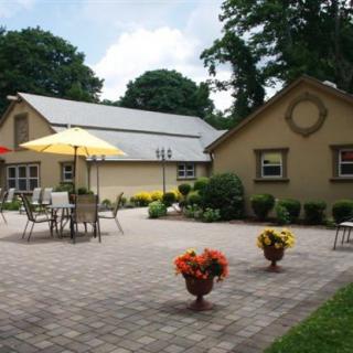 A spacious patio area with tables, chairs, and umbrellas surrounded by a well-maintained garden.