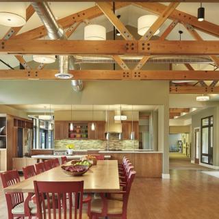 A spacious and modern dining area with exposed wooden beams and a fully equipped kitchen.