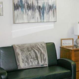 A cozy living room with a green sofa, adorned with a blanket, and abstract artwork above.