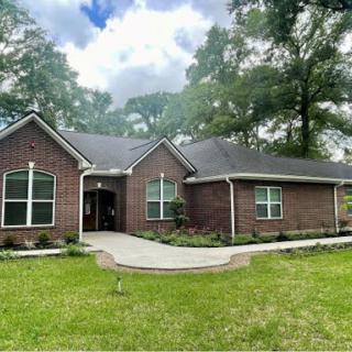 A charming brick house surrounded by lush greenery and a well-maintained front yard.