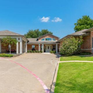 A sunny day at a residential building with a driveway and well-maintained lawn.