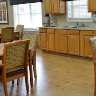A spacious dining area with wooden tables and chairs, adjacent to a well-equipped kitchen.