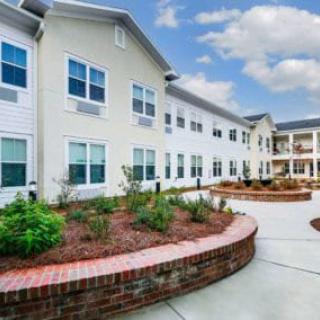 A modern residential building with well-maintained landscaping and a clear sky above.