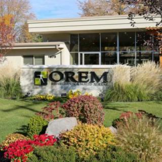 The Orem city office building with a landscaped entrance featuring autumn foliage and colorful flowers.