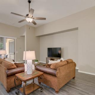 A cozy living room with sofas, a television, and a ceiling fan.