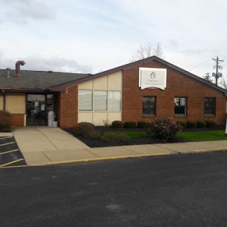 A commercial brick building with a prominent sign and landscaped surroundings.