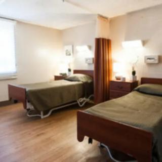 A clean and organized hospital room with two beds and a curtain divider.