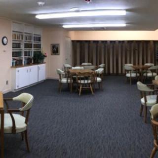 A well-lit indoor meeting room with several tables and chairs.