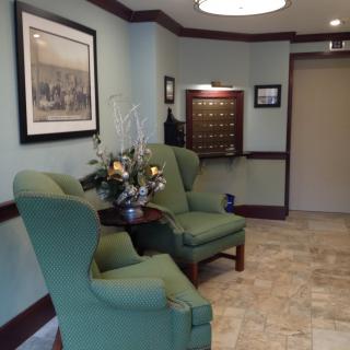 A cozy lobby with green chairs and floral decoration.