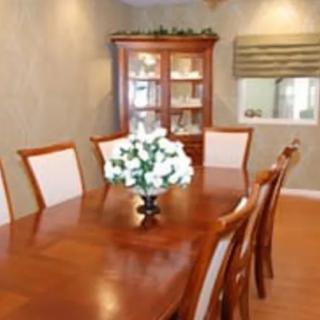 A dining room featuring a wooden table, chairs, and a cabinet, with a centerpiece of flowers.