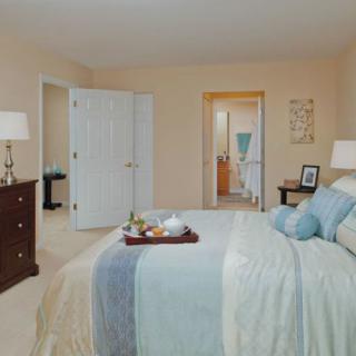 A cozy bedroom with soft blue and beige tones, featuring a neatly made bed and elegant decor.