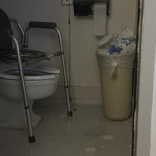 An accessible bathroom with a toilet and trash can.