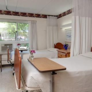 A hospital room with two beds, curtain dividers, and furniture.