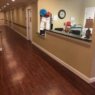 A long hallway with a reception desk and wooden flooring.