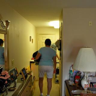 A person walking through a hallway in a home, surrounded by furniture and decor.