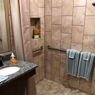 A modern bathroom with tiled walls, a granite countertop, and neatly hung blue-striped towels.