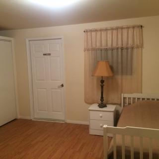 A simple bedroom with a bed, nightstand, and lamp.