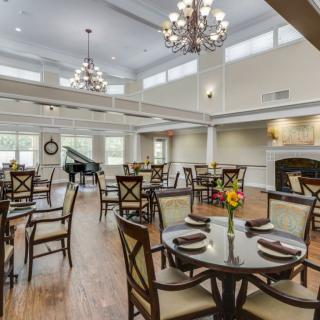 An elegant dining room with chandeliers, a grand piano, and neatly arranged tables and chairs.