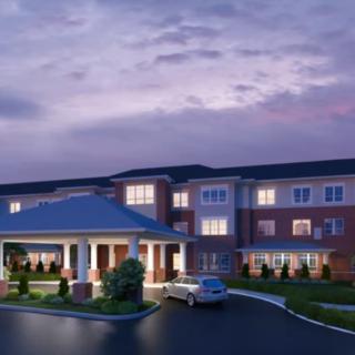 A twilight view of a residential building with a car parked at the entrance.