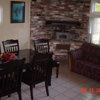 A cozy living and dining area featuring a brick fireplace, dining table with chairs, and a comfortable couch.