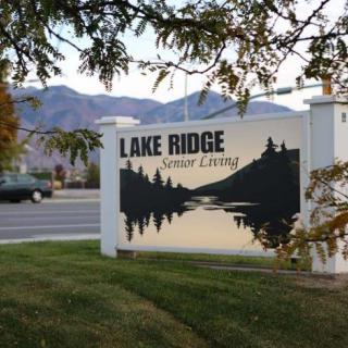 A sign for Lake Ridge Senior Living with a scenic nature design in the foreground.