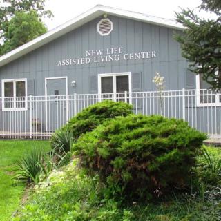 A building labeled 'New Age Family Living Center' surrounded by bushes and a white fence.