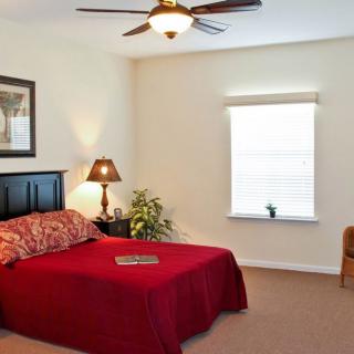 A cozy bedroom with a red bedspread and warm lighting.