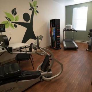 A small fitness room featuring a treadmill, stationary bike, and exercise machine.