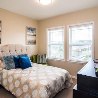 A cozy and well-decorated bedroom featuring a comfortable bed, stylish pillows, and natural light coming through the windows.