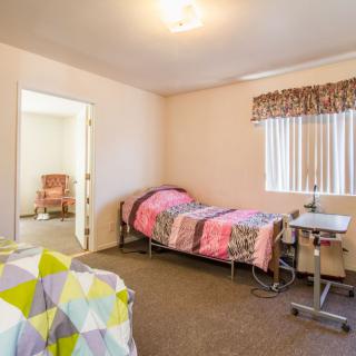 A simple care facility room with two beds and a window, providing a cozy environment.