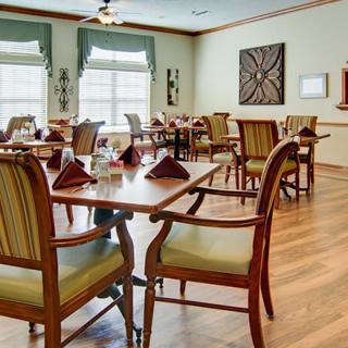 A well-decorated dining room with neatly arranged tables and chairs, featuring elegant place settings and wooden flooring.