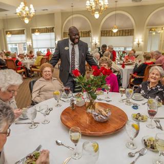 A group of seniors enjoying a formal dining experience with lively conversation.